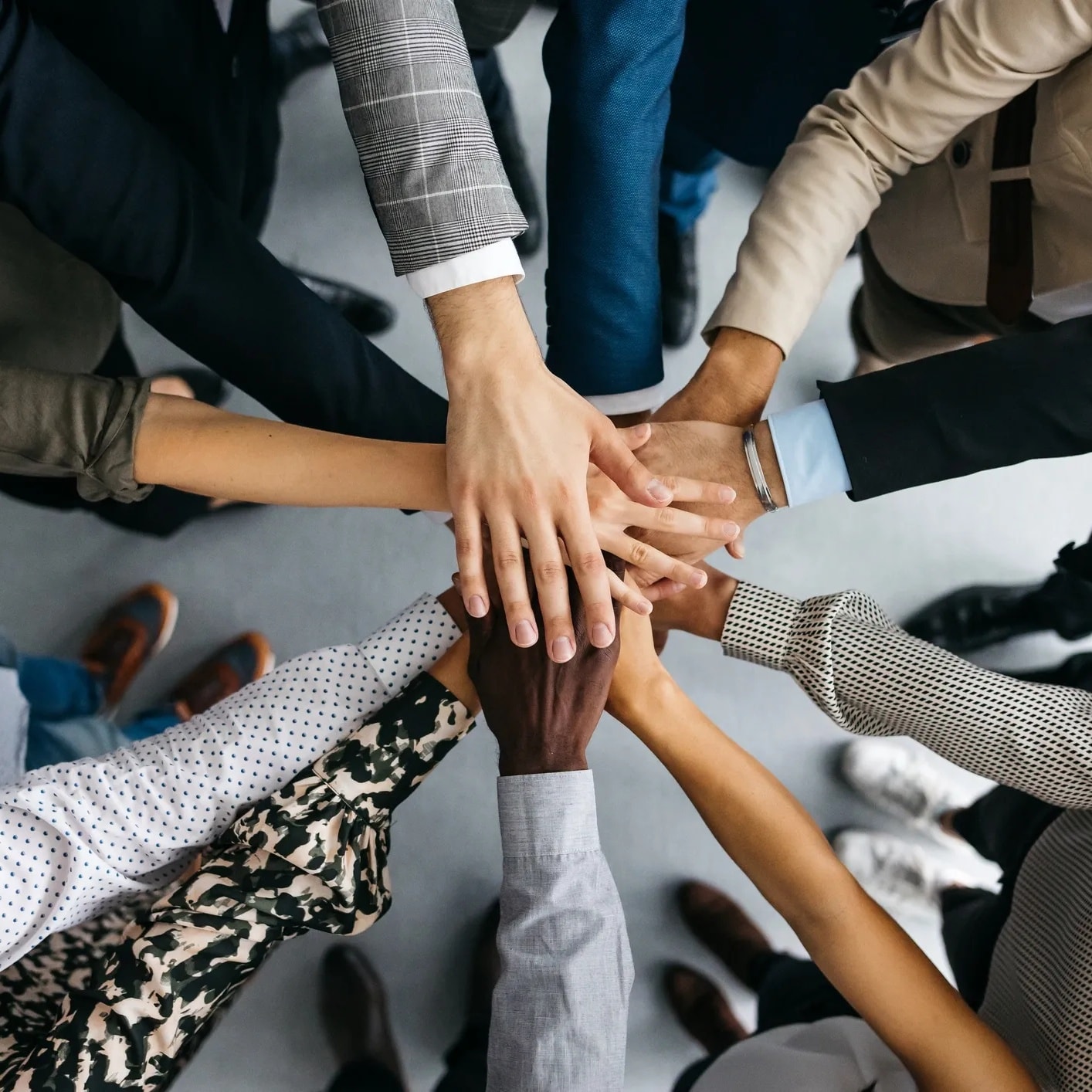 Diverse multiracial group of people placing their hands together in the center — symbolizing unity, connection, and community support