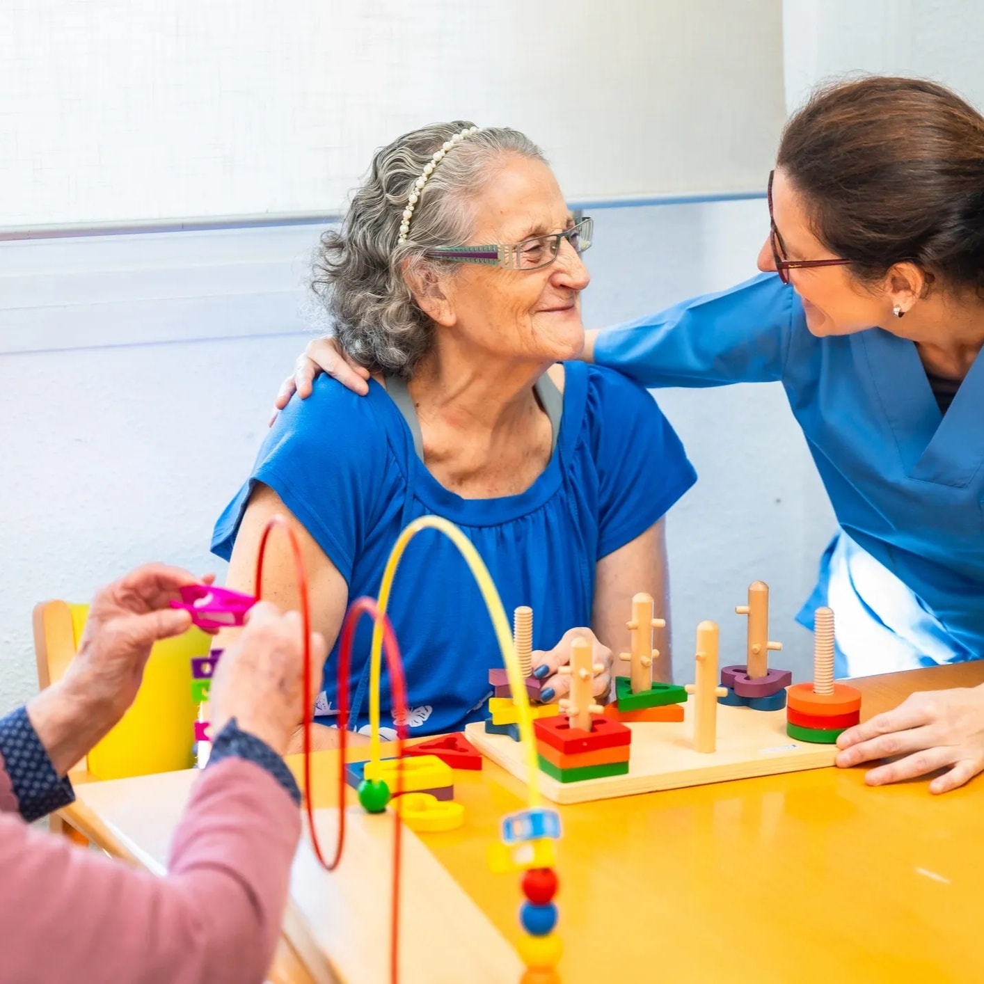 Caregiver and elderly person calmly looking through a photo album together at home — both faces visible