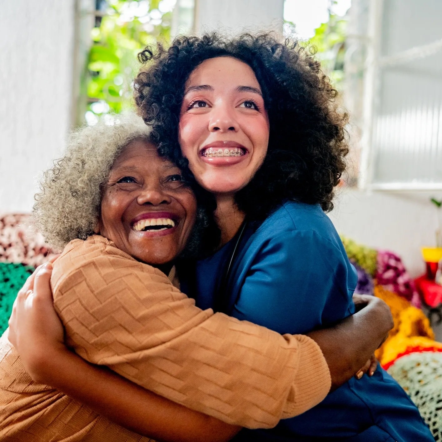 Caregiver warmly assisting a senior woman with getting dressed at home — dignified daily living support
